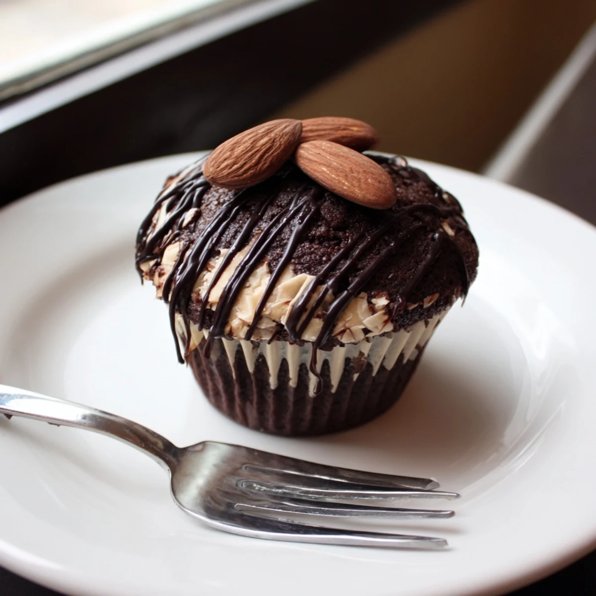 Rich flourless almond joy cupcakes drizzled with melted chocolate and topped with roasted almonds