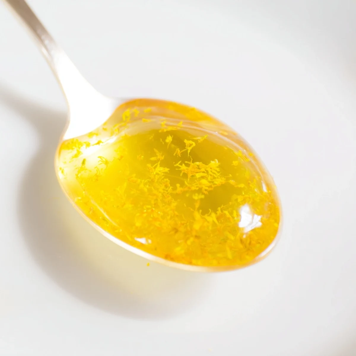 A jar of fresh dandelion jelly glowing with bright spring sunshine yellow