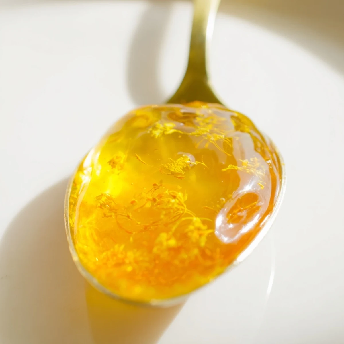Warm homemade dandelion jelly ladled into a sterilized canning jar with foam skimmed