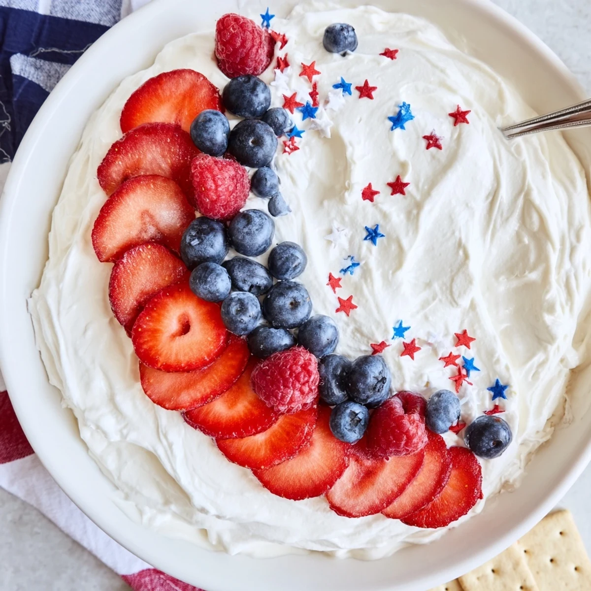 Star Spangled Cheesecake Dip glistening with strawberries, blueberries, and festive star sprinkles.