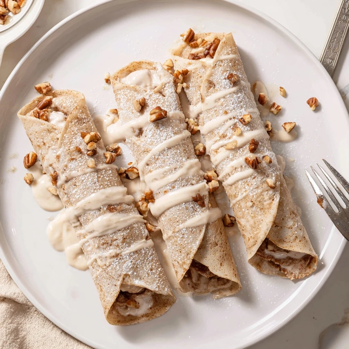 Thin cinnamon roll protein crepes rolled with creamy spiced filling and topped with glaze
