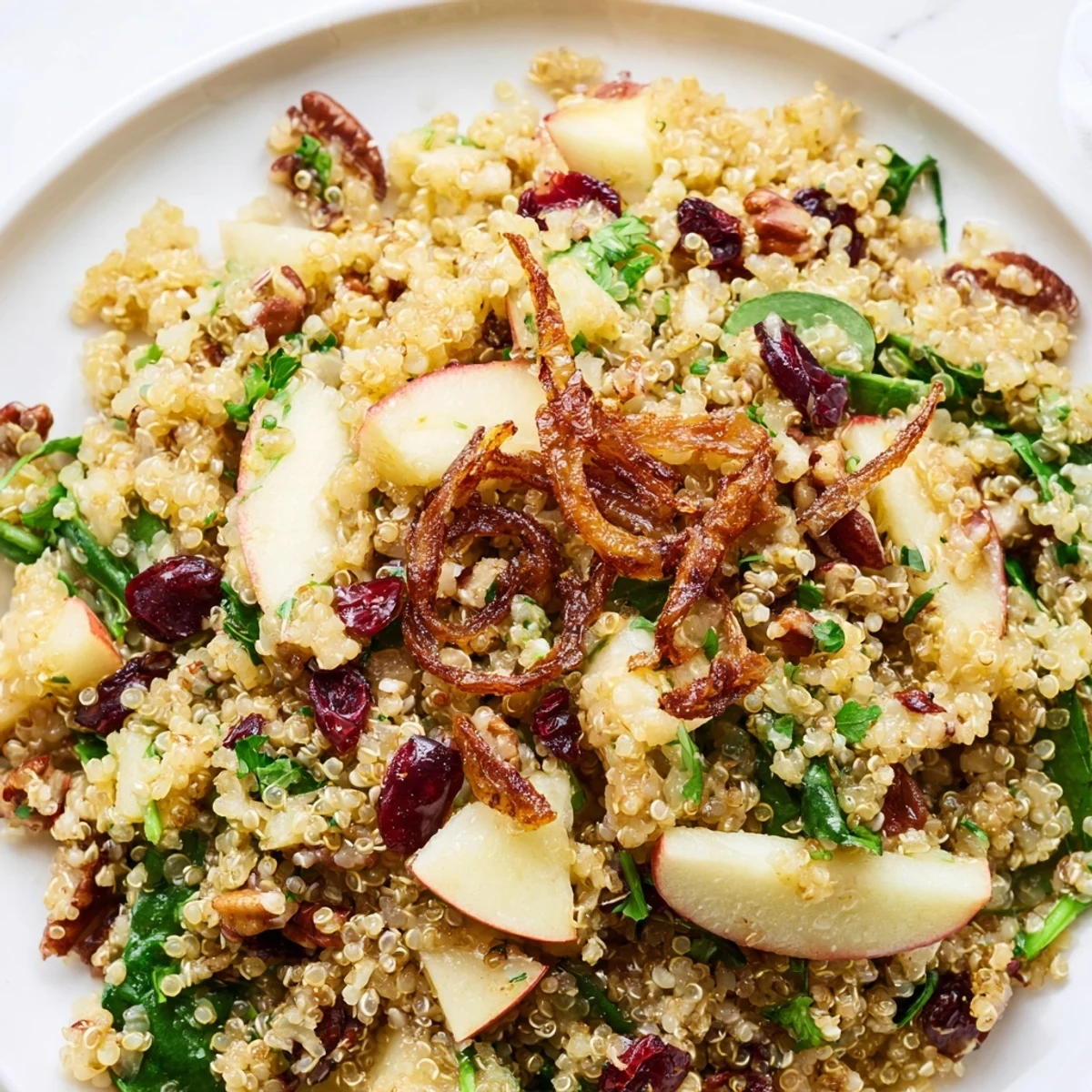 Golden crispy shallots crown a fresh honey mustard quinoa apple salad in a wooden bowl
