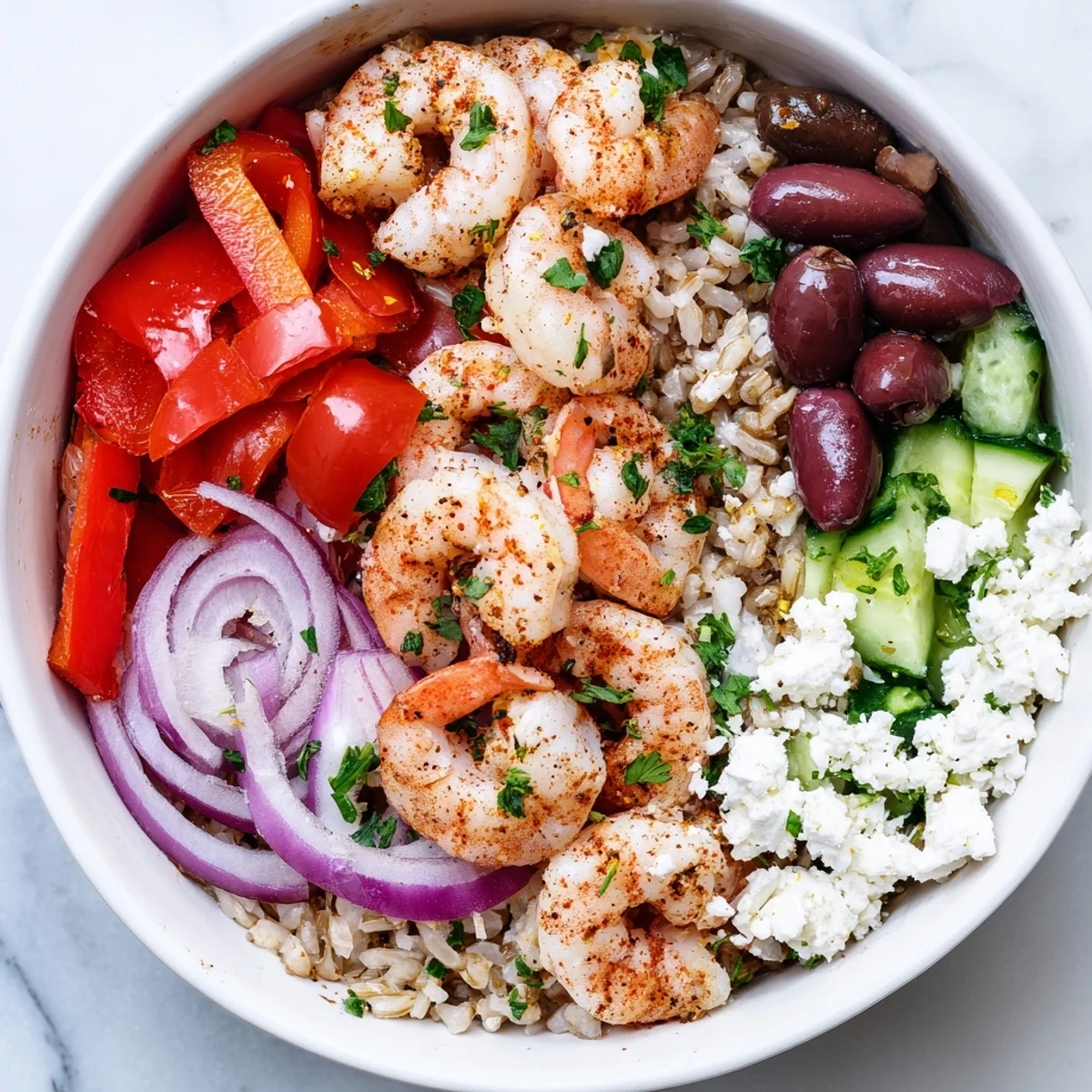 Warm Greek Shrimp Mediterranean Bowl loaded with olives roasted peppers and tangy feta crumbles