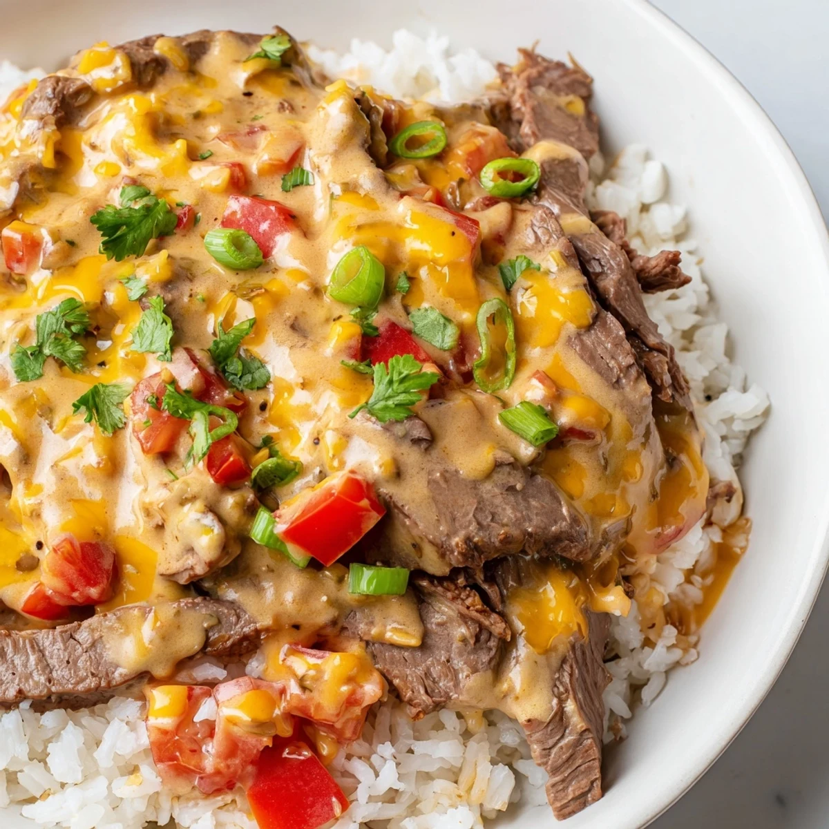 Creamy steak queso rice piled high with melted cheese and fresh cilantro