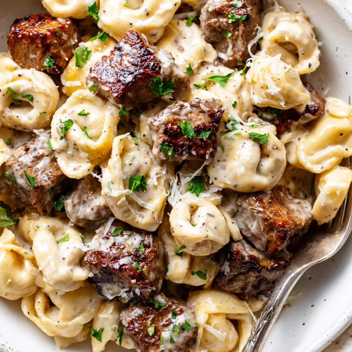 Seared steak bites and cheese tortellini coated in a velvety garlic cream sauce
