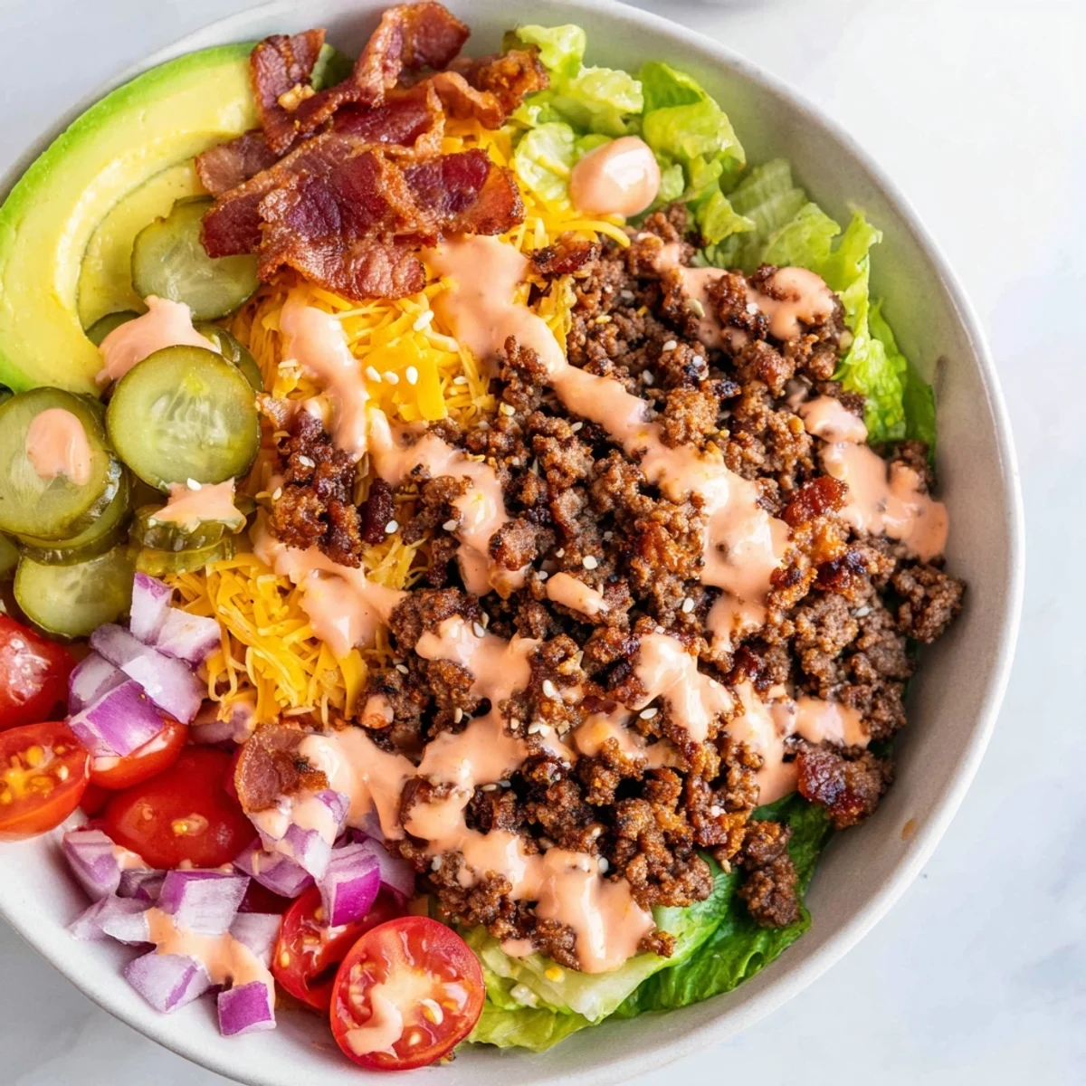 Hearty burger bowls topped with crumbled bacon, sliced avocado, and rich golden burger sauce
