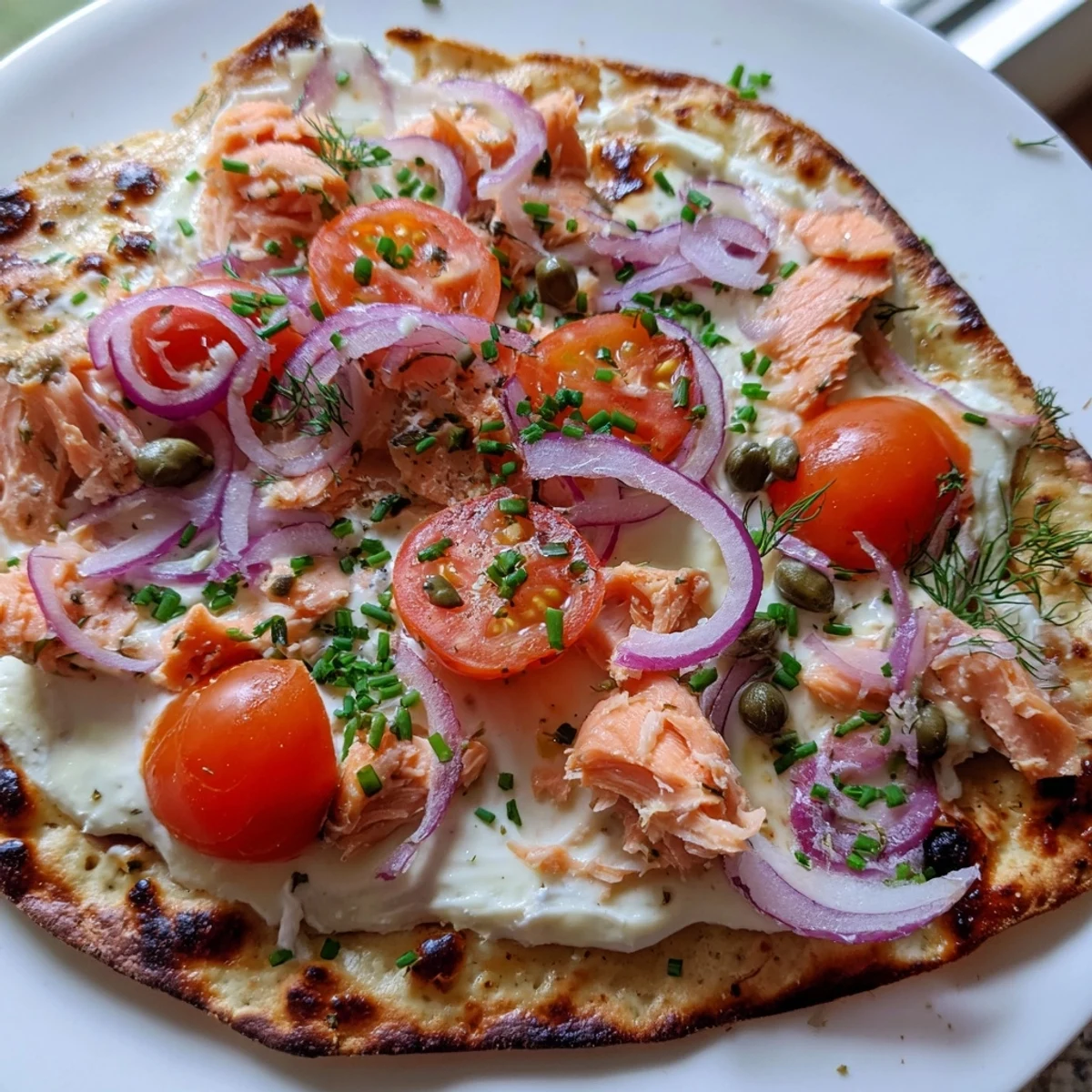 Crispy salmon tortilla pizza fresh from the oven with melted golden mozzarella and fresh herbs