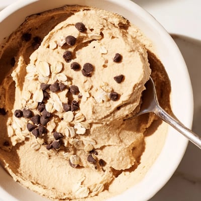 This Chocolate Chip Cookie Dough Hummus is served with crisp apple slices and pretzels for a sweet snack.