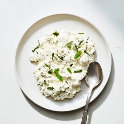 Spoonful of Tofu Ricotta being lifted from a bowl, highlighting its smooth texture, ideal for vegan lasagna or stuffed shells.