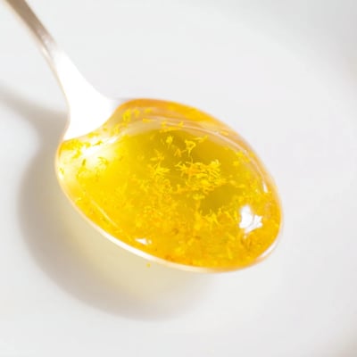 A jar of fresh dandelion jelly glowing with bright spring sunshine yellow