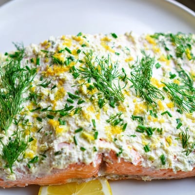 Perfectly baked Boursin salmon fillets topped with herbed cheese and bright lemon wedges on a parchment-lined baking sheet